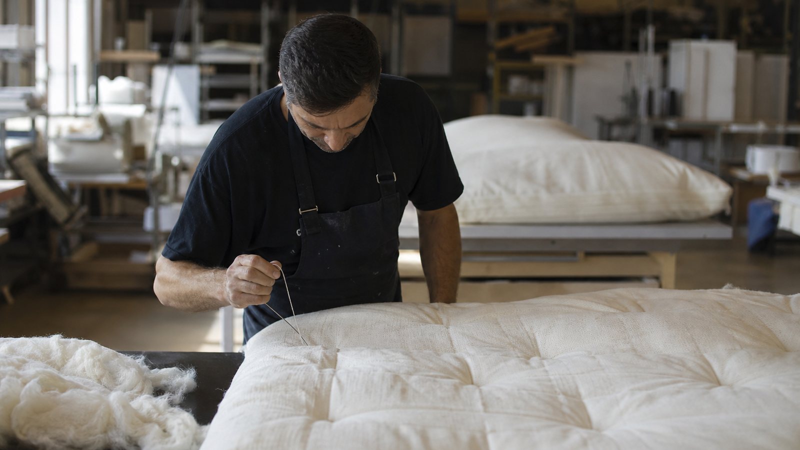 Matelas sur mesure en cours de garnissage sur l'établi d'un atelier de literie